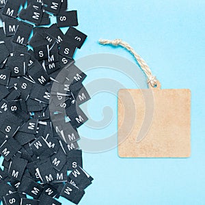 Clothes tags with different sizes. Top view. Flat lay. Clothing size S, M. Place for text. Copy space. Blue background