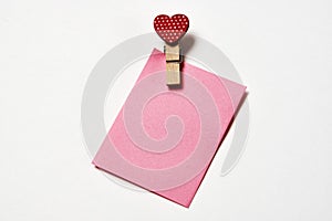 Clothespin with red heart and note paper on a white background