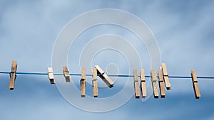 Clothespins on clothesline on sky background