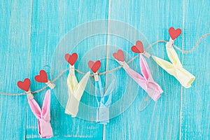 Clothespins with hearts on rough rope and blue vintage wooden background. Concept of love.