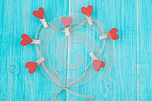 Clothespins with hearts on rough rope and blue vintage wooden background. Concept of love.