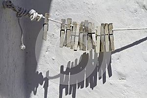 Clothespins on rope on background wall white