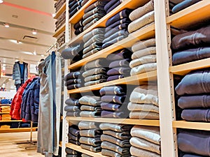 Clothing aisle with folded up jeans and sweaters for sale in a fashion retail outlet
