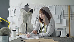 Clothing designer in small start-up business is drawing sketches for women`s clothes and thinking about next fashion