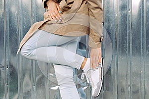 Clothing details: girl in a beige coat, jeans and sneakers outdoors