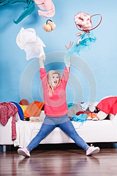 Woman sitting on messy couch throwing clothes