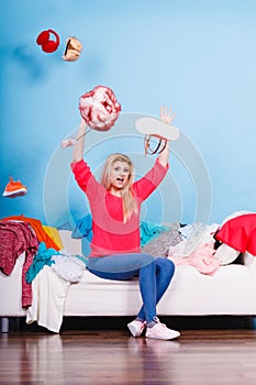 Woman sitting on messy couch throwing clothes