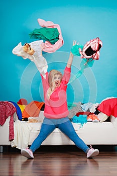 Woman sitting on messy couch throwing clothes