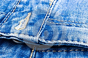 clothing items blue stonewashed faded jeans cotton fabric texture with seams, clasps, buttons and rivets, macro, close-up