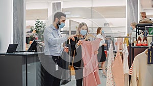 Clothing Store: Female Customer Shopping, Retail Sales Assistant Helps. Wearing Protective Face