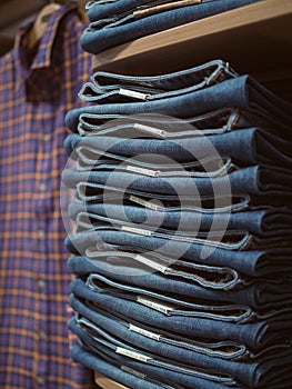Clothing store. Folded jeans on shelf in background of checkered