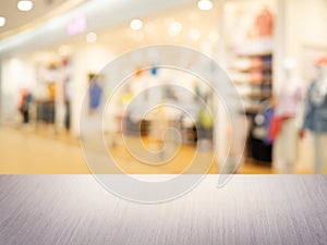 Clothing store in the mall, Empty top gray wooden table and blur with bokeh background. For product display.