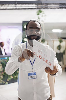 Clothing store smiling owner holding we are closed sign