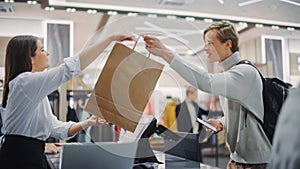 Clothing Store: Young Man At Checkout Counter Buys Clothes. Friendly Retail Sales Assistan Passes