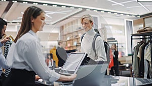 Clothing Store: Young Man At Checkout Counter Buys Clothes Paying with Contactless NFC Smartphone