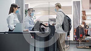 Clothing Store: Young Man At Counter Buys Clothes from Friendly Retail Sales assistants, Paying with