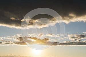 The cloud with beautiful sunlight and golden sky background, Beautiful sunlight passing through a big black rain cloud. Sunset in