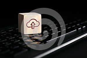 Cloud computing upload icon on wooden cube with computer keyboard. Remote download technology concept