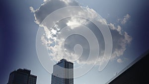 Cloud crosses the sun over a high rise building in Brooklyn with an empty blue sky