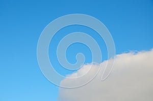Cloud with curved growing edge in blue sky