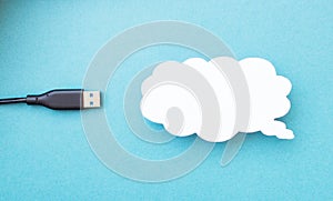 Cloud for data storage cut from paper on a blue background and cable usb, close-up, data storage on the Internet