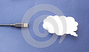 Cloud for data storage cut from paper on a blue background and cable usb, close-up, data storage on the Internet