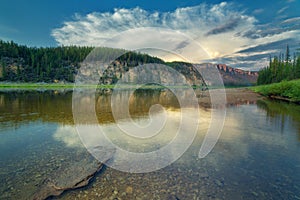 Cloud over the rocky bank of the taiga river River Amga.