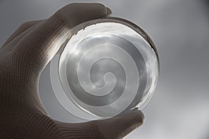 Cloud reflected in a crystal ball in a gloved hand