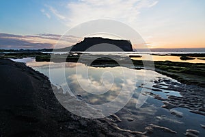 Cloud reflections in water at sunrise at Ilchulbong volcano crater, Seongsan, Jeju Island, South Korea photo