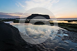 Cloud reflections in water at sunrise at Ilchulbong volcano crater, Seongsan, Jeju Island, South Korea