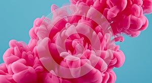 Cloud of vibrant pink ink dispersing in water against a light blue background. The ink photo