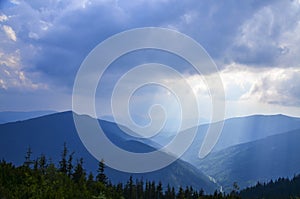 Clouds Above Sun Rays Shining on the Blue Carpathian Mountains on a cloudy fall evening in October