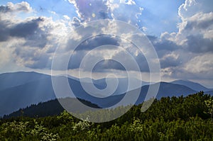 Clouds Above Sun Rays Shining on the Blue Carpathian Mountains on a cloudy fall evening in October