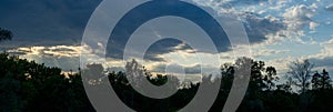 Clouds against the background of the evening sky and silhouettes of trees