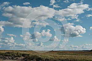Clouds against a blue sky floating above marsh nature landscape photo