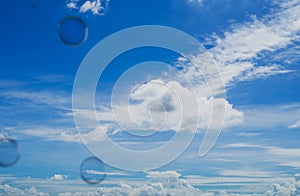 Clouds in the blue sky with bokeh floating soap bubbles in the foreground