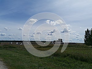 Clouds on blue sky, field, barns in summer