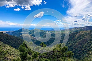 Clouds on blue sky over mountains and sea in Sierra de las Nieves National Park