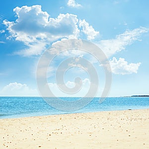 Low clouds in blue sky over sea and sand