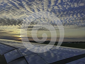 Clouds and blue sky reflecting on airplane wing at sunset