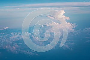 Clouds and blue sky view out from window of airplane flying over earth ground.