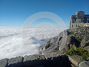 Clouds creeping up the Mountainside to engulf the Cableway buildings that are on the edge of table mountain photo