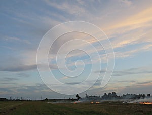 Clouds in the evening sky over a burning field