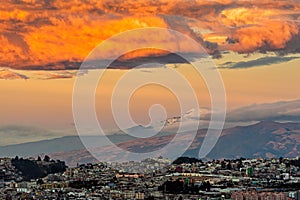 Clouds on fire above the modern city of Quito and the Cayambe volcano