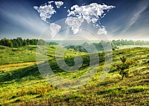 clouds in the form of a world map over a green field. Travel and landscape concept