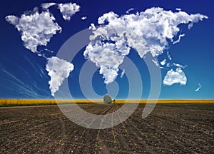 clouds in the form of a world map over a rapeseed field. Travel and landscape concept