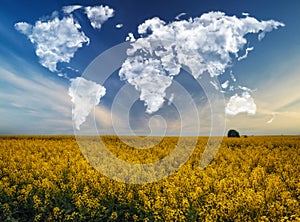 clouds in the form of a world map over a rapeseed field. Travel and landscape concept