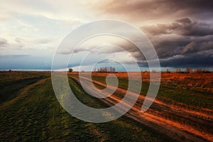 Clouds gather above a serene, open landscape with a long path