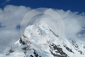 Clouds on high mountain snow peak