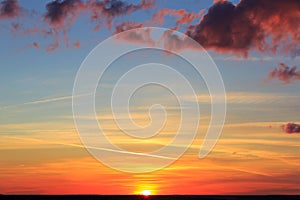 The clouds are illuminated by the bright red light of the setting sun